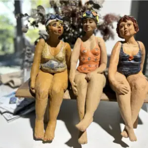 three ceramic bathing beauties on a bench, hand-built sculptures